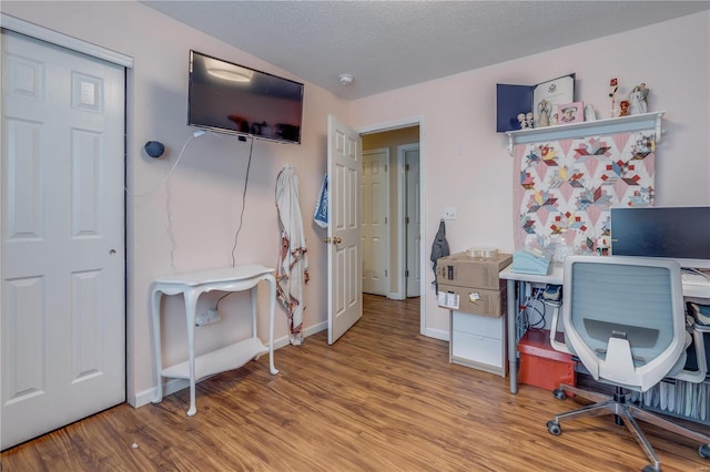 office area with a textured ceiling, baseboards, and wood finished floors