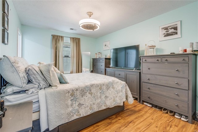 bedroom with a textured ceiling, visible vents, and light wood-style floors