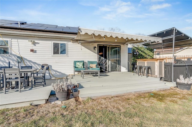 rear view of property with outdoor dining area, a deck, and solar panels