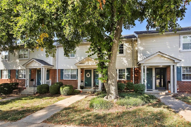 townhome / multi-family property featuring brick siding and a front lawn