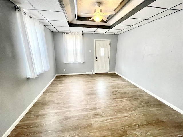 foyer featuring baseboards, a tray ceiling, a ceiling fan, and wood finished floors