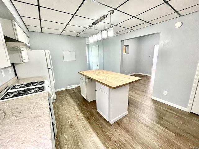 kitchen with dark wood-style floors, a center island, white cabinetry, pendant lighting, and wooden counters