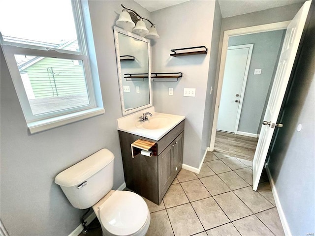 half bathroom featuring toilet, tile patterned flooring, baseboards, and vanity