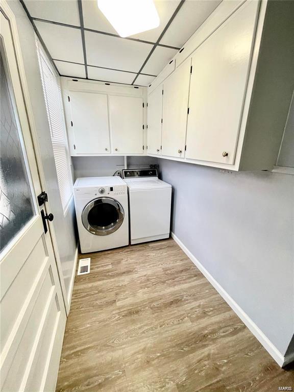 laundry room with washing machine and dryer, baseboards, cabinet space, and light wood finished floors