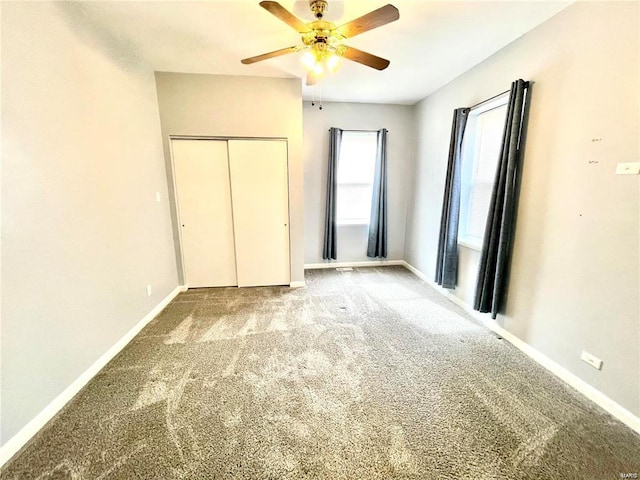 unfurnished bedroom with ceiling fan, carpet floors, a closet, and baseboards