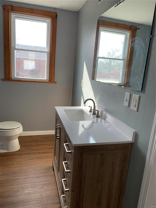 bathroom featuring toilet, vanity, baseboards, and wood finished floors