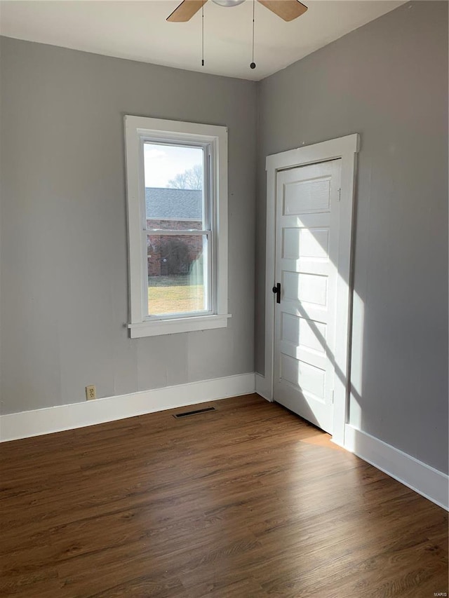 unfurnished room featuring baseboards, visible vents, ceiling fan, and dark wood-style flooring