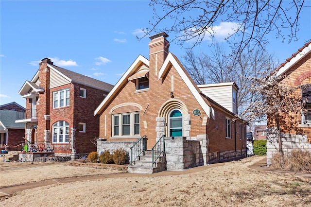 tudor house featuring brick siding and a chimney