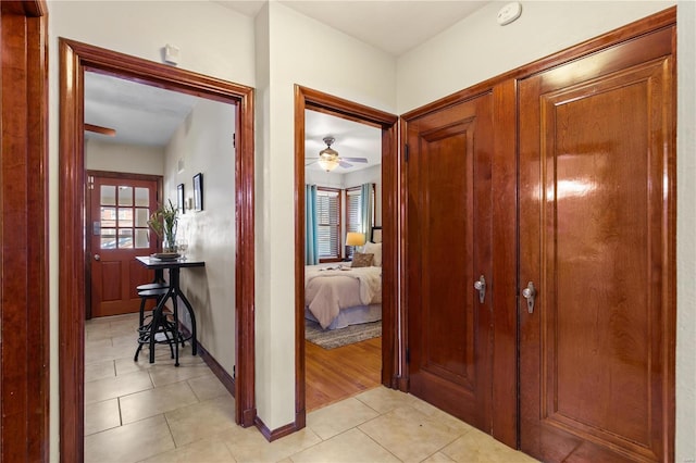 corridor featuring light tile patterned floors and baseboards