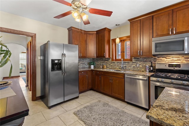 kitchen featuring stainless steel appliances, light stone counters, a sink, and decorative backsplash