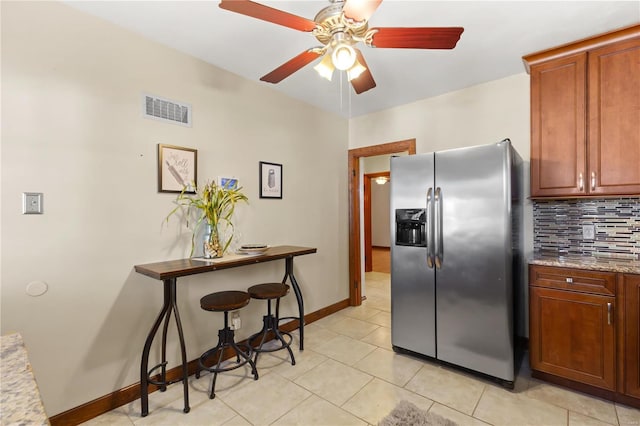 kitchen with stainless steel refrigerator with ice dispenser, visible vents, backsplash, ceiling fan, and baseboards