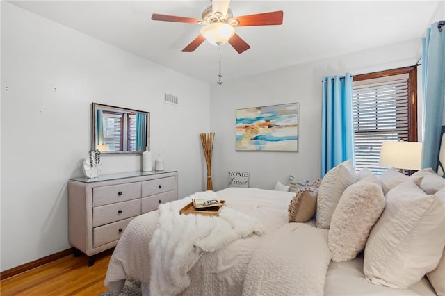 bedroom with a ceiling fan, visible vents, light wood-style flooring, and baseboards