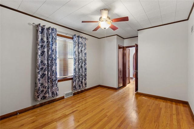 unfurnished room with light wood-type flooring, baseboards, visible vents, and crown molding