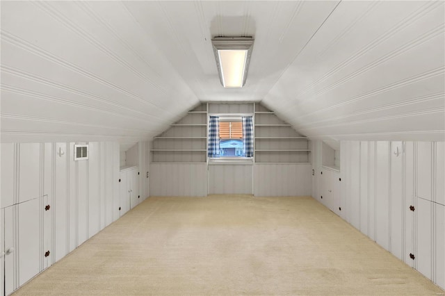 additional living space with lofted ceiling, wood walls, carpet flooring, and visible vents