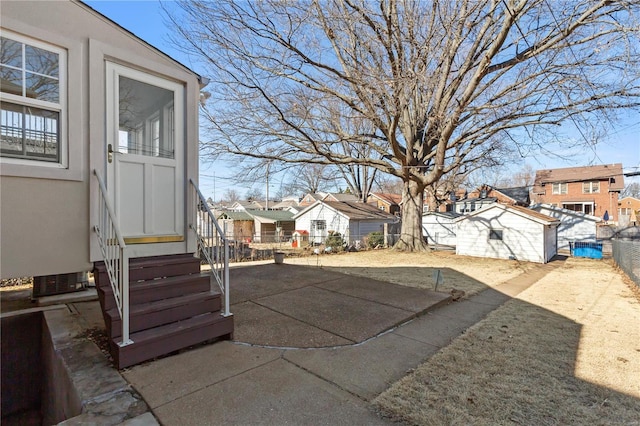 view of yard with entry steps, fence, and a residential view