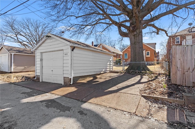 detached garage featuring driveway, a gate, and fence