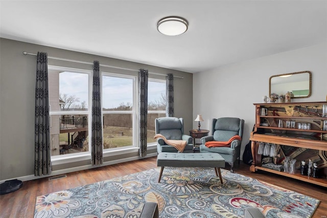 living area with baseboards, visible vents, and wood finished floors