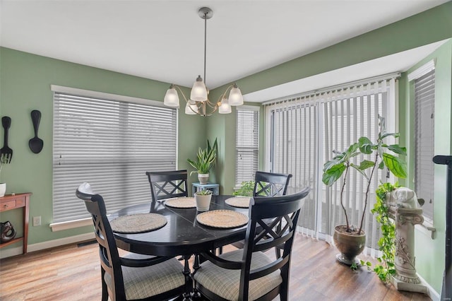 dining room featuring light wood-type flooring, baseboards, and an inviting chandelier