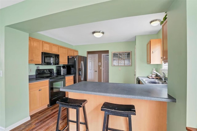 kitchen featuring dark wood-style flooring, light brown cabinets, a sink, a peninsula, and black appliances