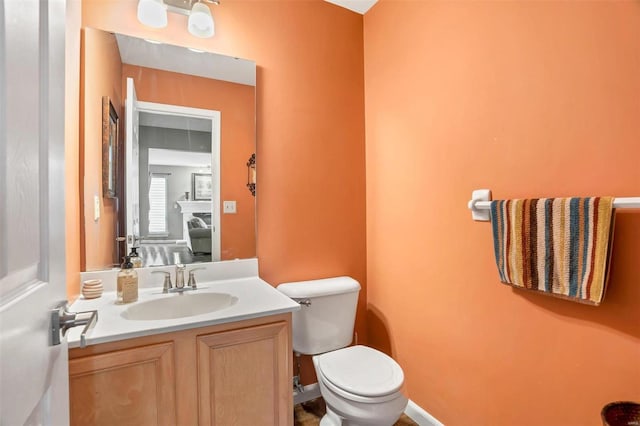 bathroom with toilet, baseboards, and vanity