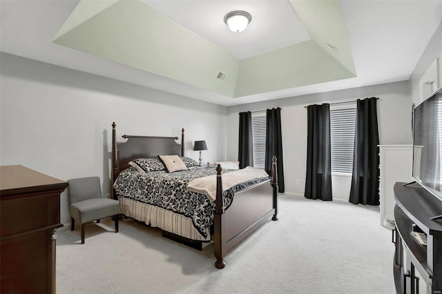 bedroom with a raised ceiling, visible vents, and light colored carpet