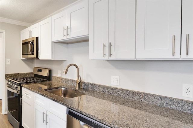 kitchen featuring a sink, stainless steel appliances, ornamental molding, and white cabinetry