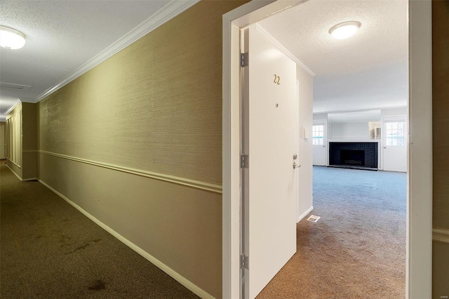 corridor with carpet flooring, a textured ceiling, visible vents, and ornamental molding