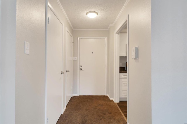 hall featuring a textured ceiling, ornamental molding, and dark carpet