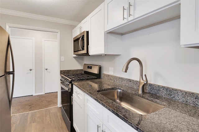 kitchen featuring ornamental molding, a sink, white cabinets, appliances with stainless steel finishes, and a textured ceiling