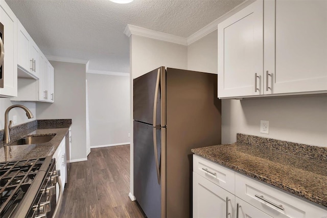 kitchen with dark stone countertops, stainless steel appliances, crown molding, and a sink