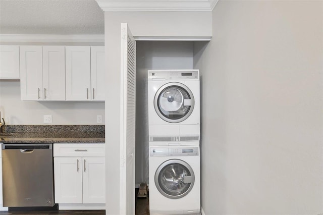 clothes washing area with stacked washer / dryer, a textured ceiling, laundry area, and crown molding