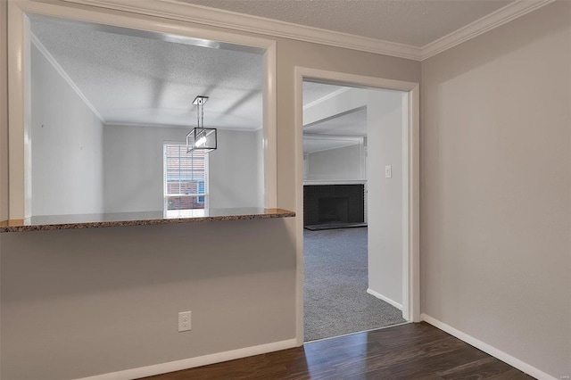 spare room featuring a fireplace, a textured ceiling, crown molding, and wood finished floors