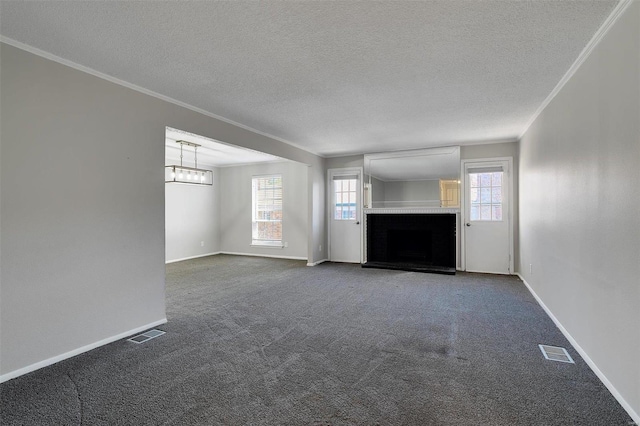 unfurnished living room featuring visible vents, a fireplace, ornamental molding, and dark carpet