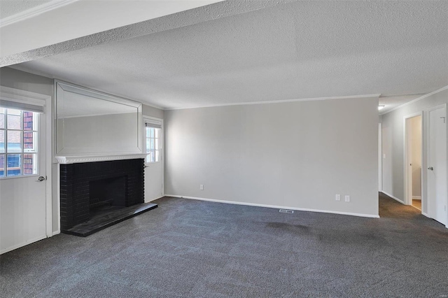 unfurnished living room with dark carpet, a fireplace, a textured ceiling, and crown molding