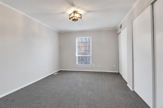 unfurnished bedroom with visible vents, a textured ceiling, dark carpet, and crown molding