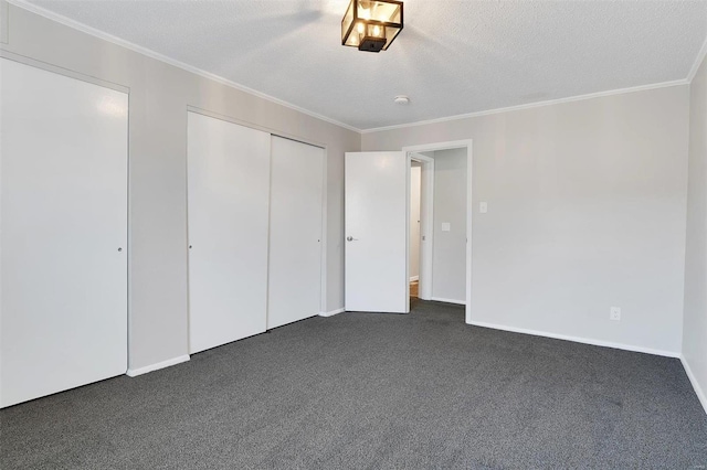 unfurnished bedroom featuring baseboards, dark carpet, ornamental molding, a closet, and a textured ceiling