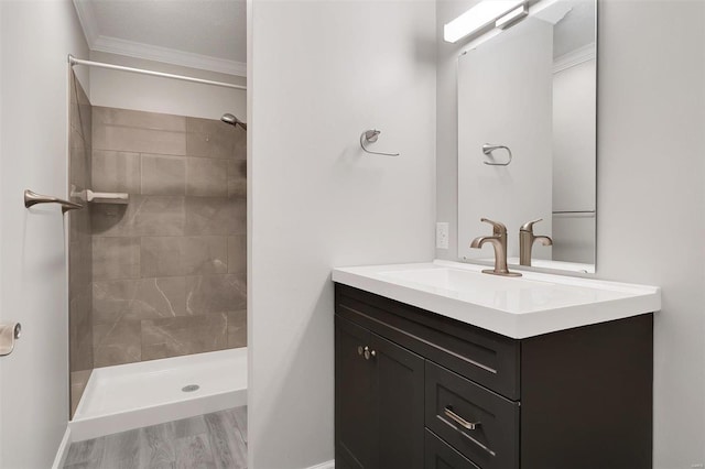 bathroom with vanity, crown molding, wood finished floors, and tiled shower