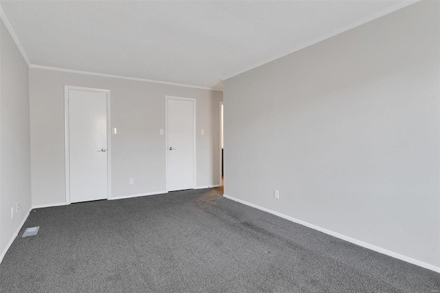 empty room featuring baseboards, dark carpet, and crown molding