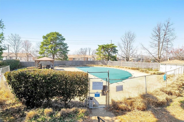 community pool featuring a gazebo, a gate, and fence