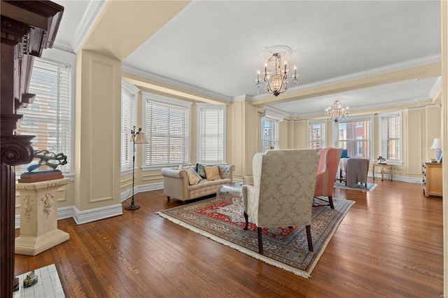 living room featuring a notable chandelier, a wealth of natural light, a decorative wall, ornamental molding, and wood finished floors