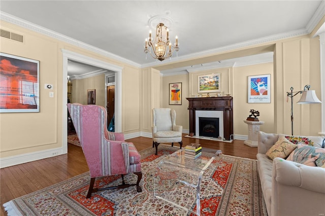 living area featuring visible vents, a fireplace with flush hearth, ornamental molding, wood finished floors, and a chandelier