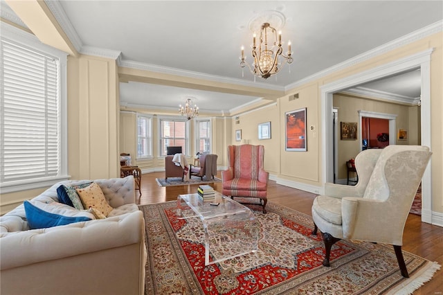 living room featuring visible vents, baseboards, ornamental molding, wood finished floors, and an inviting chandelier