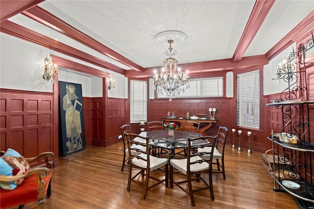 dining room with a wainscoted wall, wood finished floors, beamed ceiling, and a chandelier