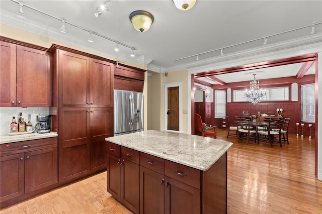 kitchen featuring light wood-style flooring, a kitchen island, ornamental molding, stainless steel refrigerator with ice dispenser, and pendant lighting