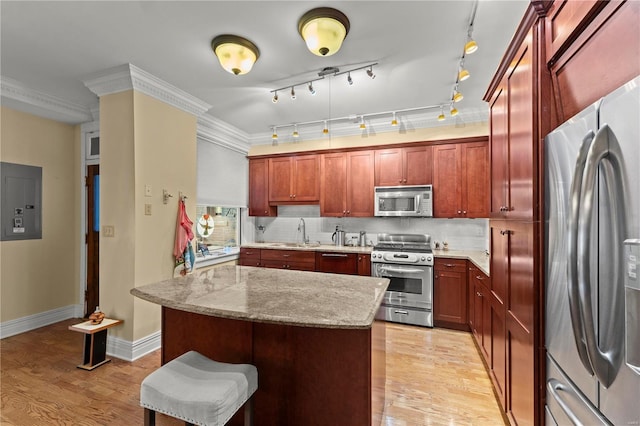 kitchen featuring stainless steel appliances, a sink, light wood-type flooring, backsplash, and electric panel