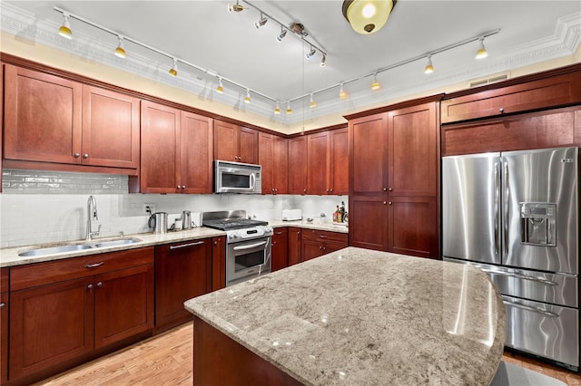 kitchen featuring light wood finished floors, decorative backsplash, appliances with stainless steel finishes, a sink, and light stone countertops