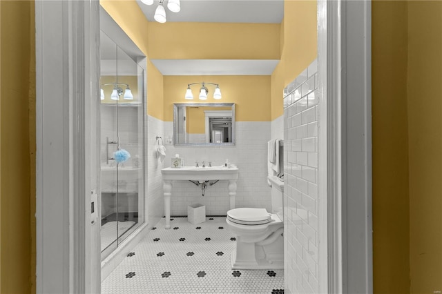 bathroom featuring tile patterned flooring, wainscoting, tile walls, and toilet