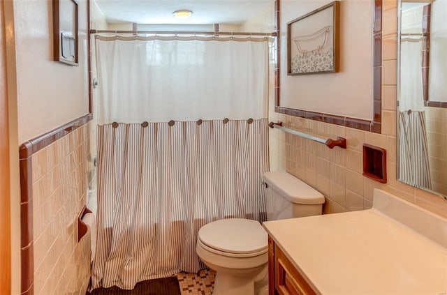 full bath featuring a wainscoted wall, toilet, tile walls, and vanity