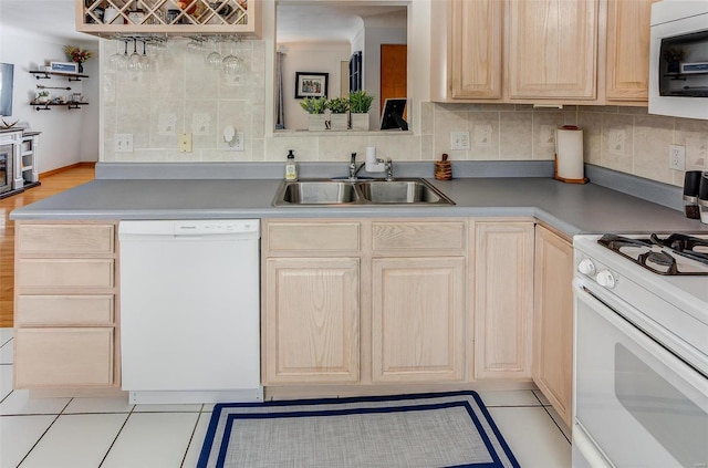 kitchen featuring light brown cabinets, white appliances, a sink, and decorative backsplash