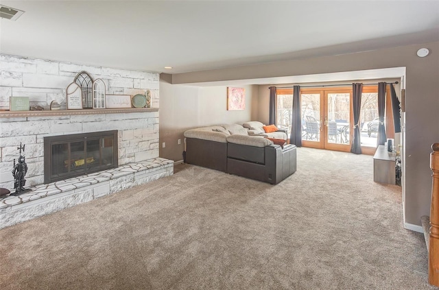 living area with french doors, a stone fireplace, carpet flooring, and visible vents